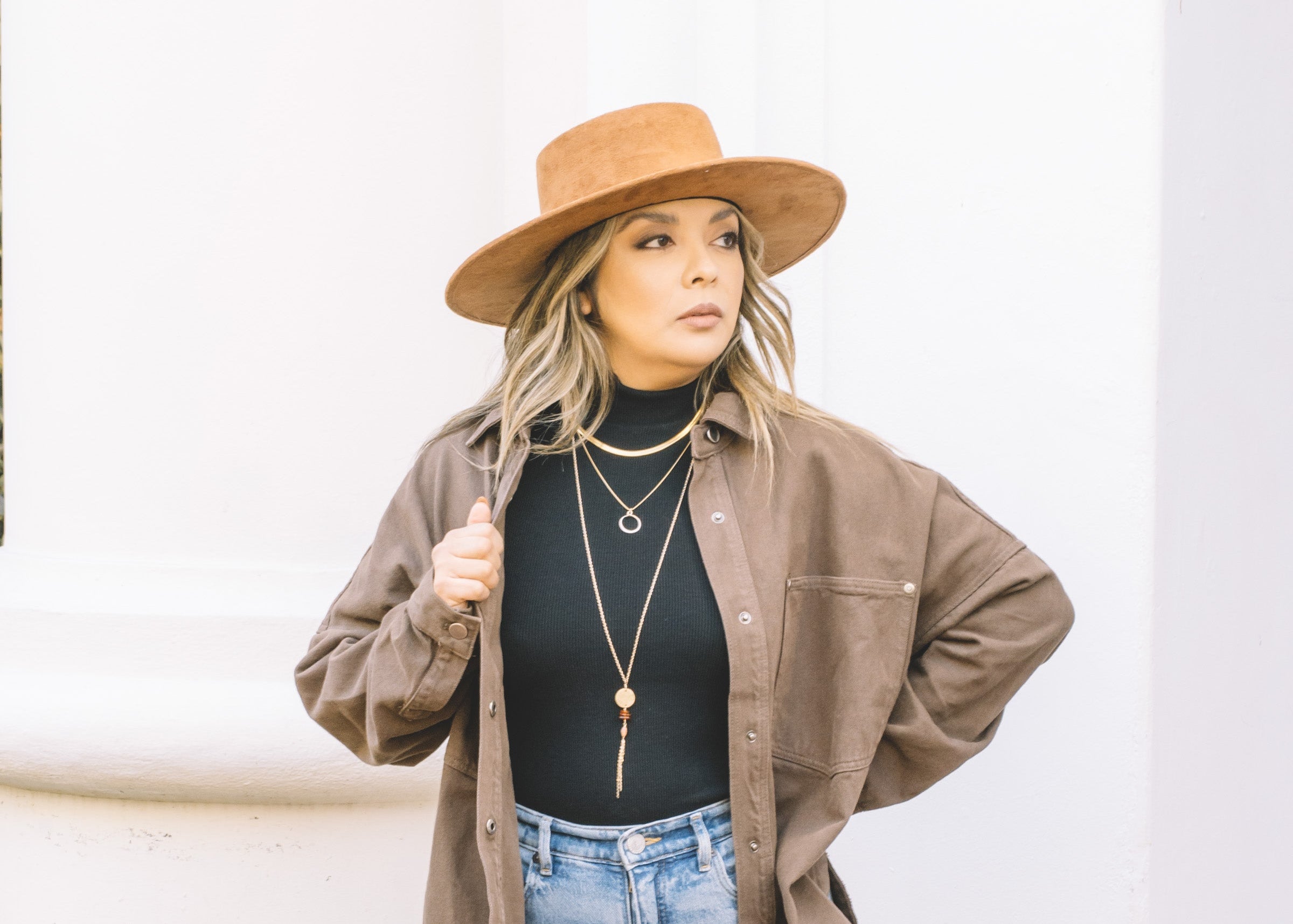 woman wearing gold necklaces layered over a black turtle neck sweater. 