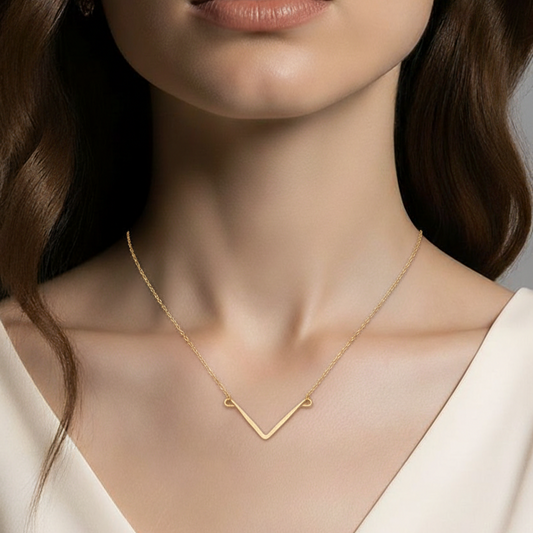 Gold-filled Necklace with a hand shaped and hammered mini V pendant worn by a model against a neutral background