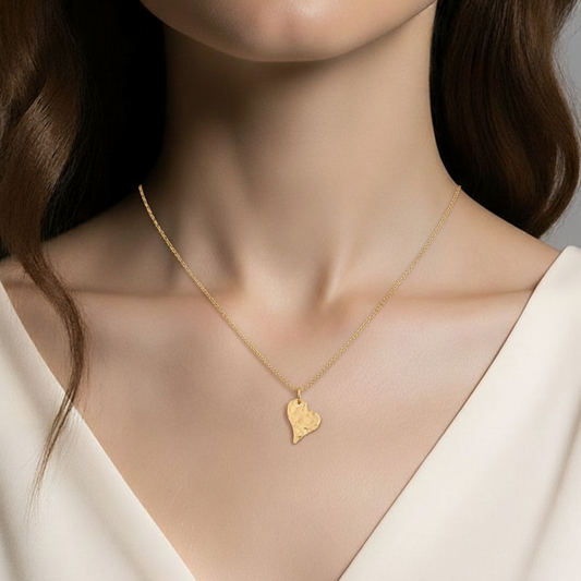 A 14k gold-filled Necklace featuring a hammered gold-filled heart shaped pendant by a model against a neutral background